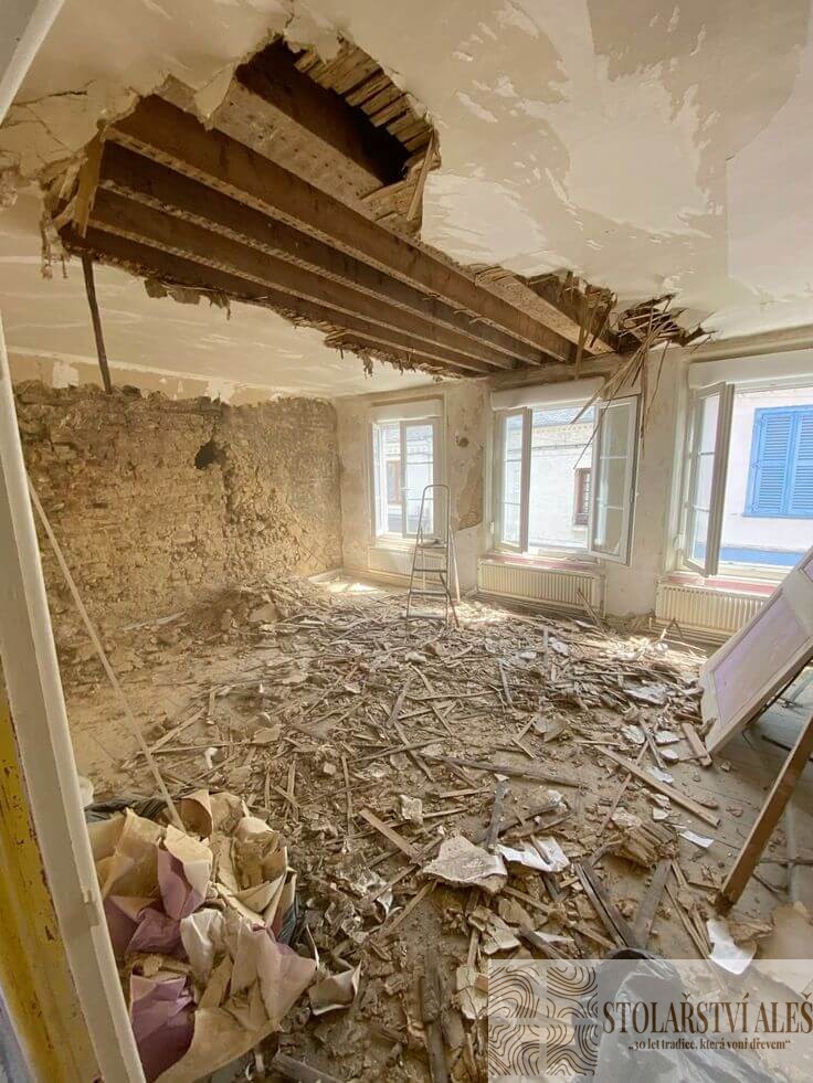 Bourací práce při rekonstrukci domu – obnažené stropní trámy, stržené omítky a suť na podlaze